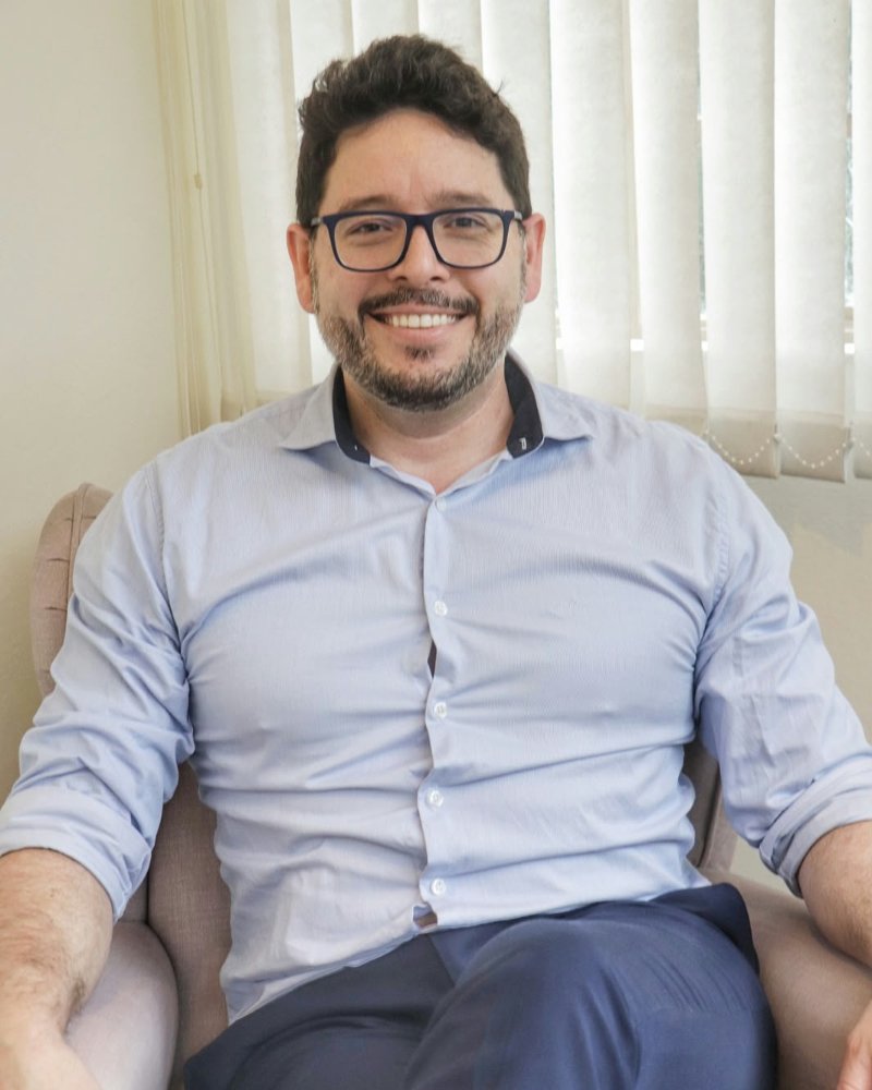 Gustavo Lowenberg Scalco, psicólogo e psicanalista, sentado em uma poltrona no consultório